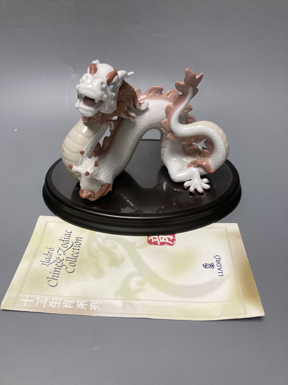 A Lladro porcelain model of a dragon, from the Chinese Zodiac collection, designed by John Coderch, width 16cm, with stand